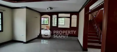 Spacious living room with elegant wooden staircase and large windows