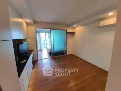 Modern apartment with wooden flooring and sliding glass doors leading to bedroom