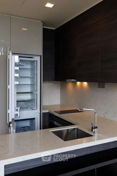 Modern kitchen with sleek cabinetry and built-in fridge, featuring elegant countertops and under-cabinet lighting.