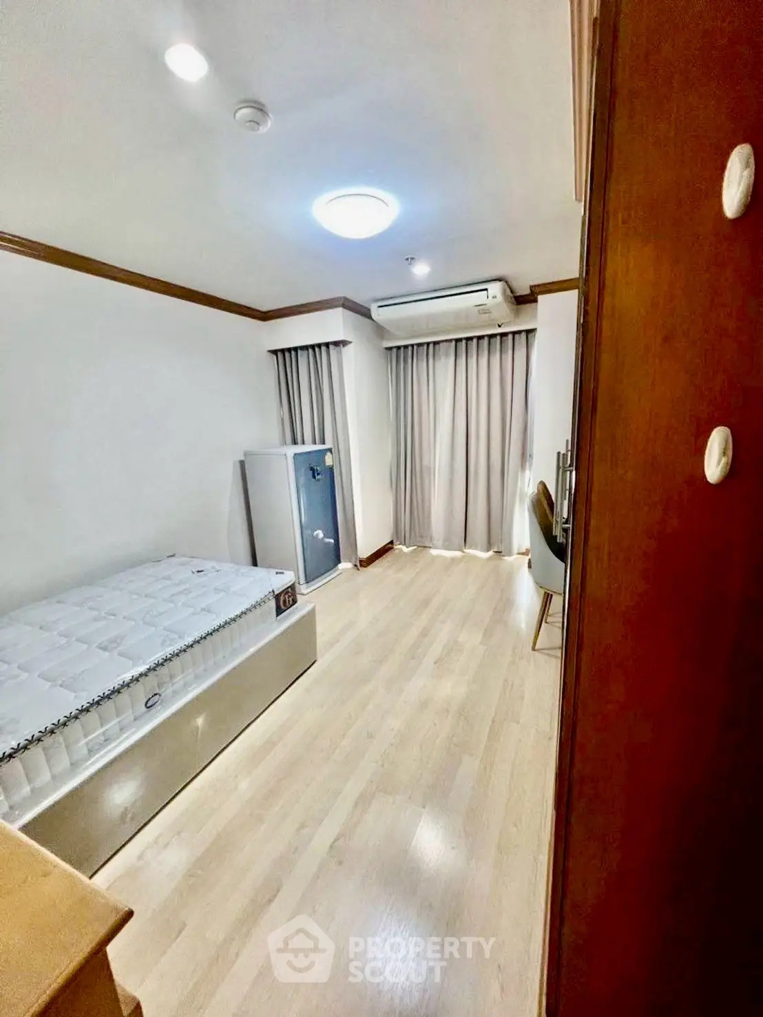 Cozy bedroom with wooden flooring and modern furnishings in a bright apartment.