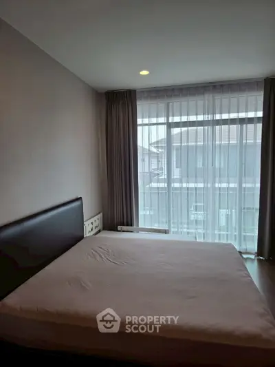 Modern bedroom with large window and elegant curtains in a stylish apartment.