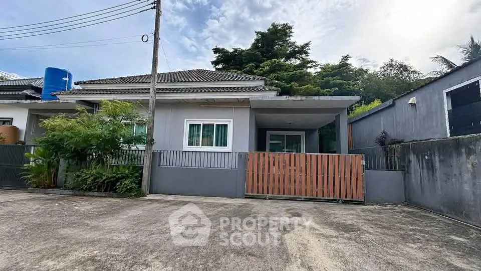 Charming single-story home with gated driveway and lush greenery, perfect for serene living.