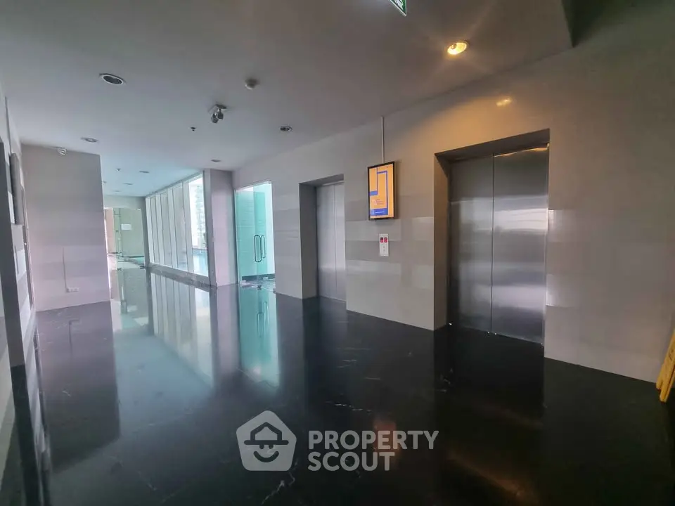 Modern building corridor with sleek elevators and glossy black flooring