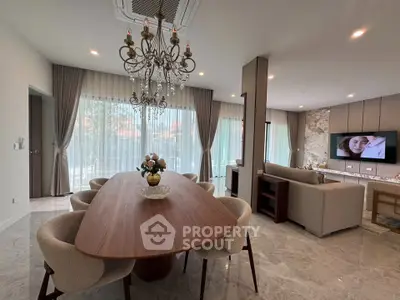Luxurious open-plan living and dining area with elegant chandelier and modern decor.