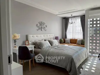 Elegant bedroom with stylish decor and natural light, featuring a cozy seating area by the window.