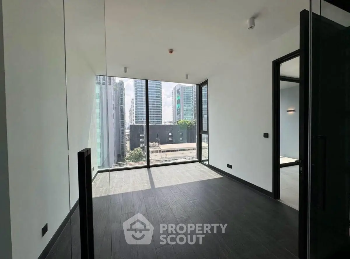 Spacious modern room with floor-to-ceiling windows offering stunning city views, perfect for urban living.
