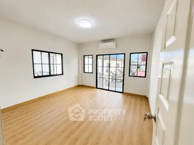 Spacious empty room with wooden flooring and large windows, perfect for customization.