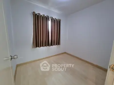 Spacious empty room with wooden flooring and window curtains
