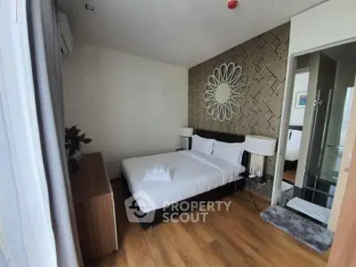 Modern bedroom with stylish decor and wooden flooring, featuring a comfortable bed and elegant lighting.