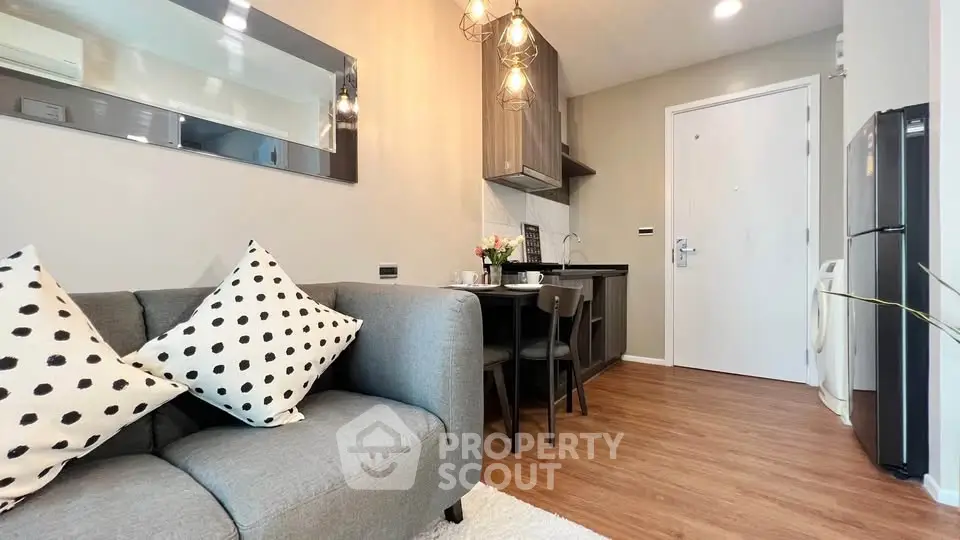 Modern open-plan living room with stylish kitchen and cozy seating area, featuring elegant lighting and contemporary decor.