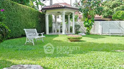 Charming garden with gazebo and benches in a serene residential setting.
