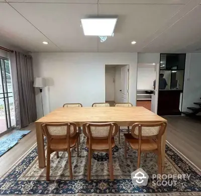 Spacious dining area with wooden table and chairs, featuring a large window for natural light.