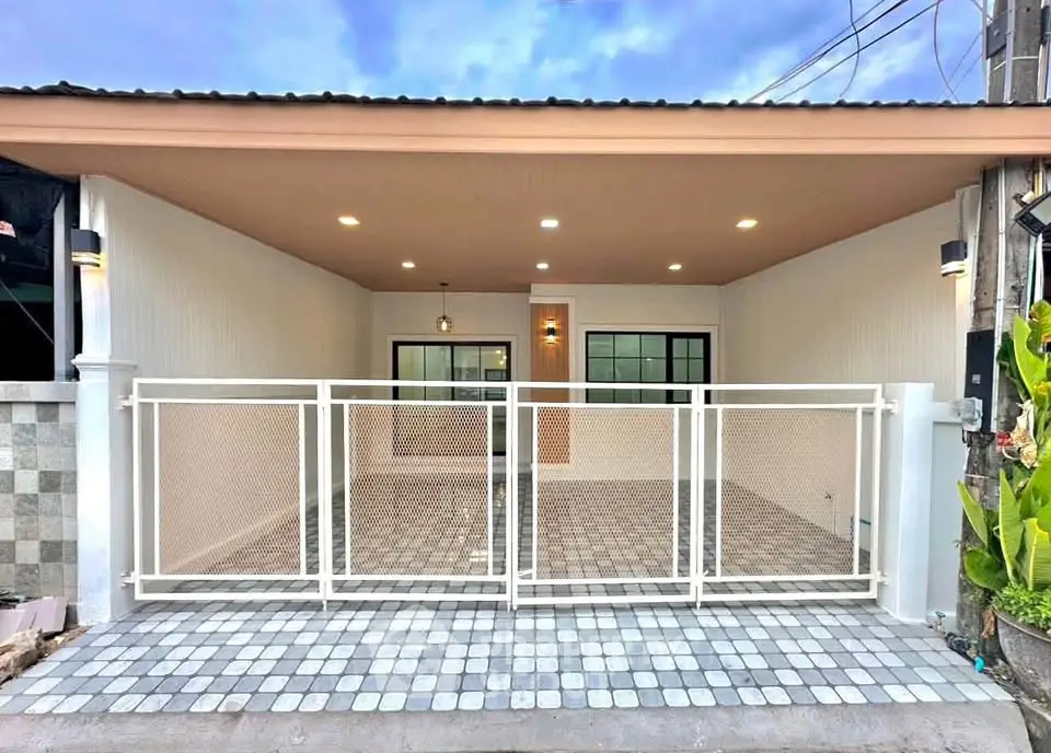 Charming single-story home with modern gated entrance and spacious tiled driveway.