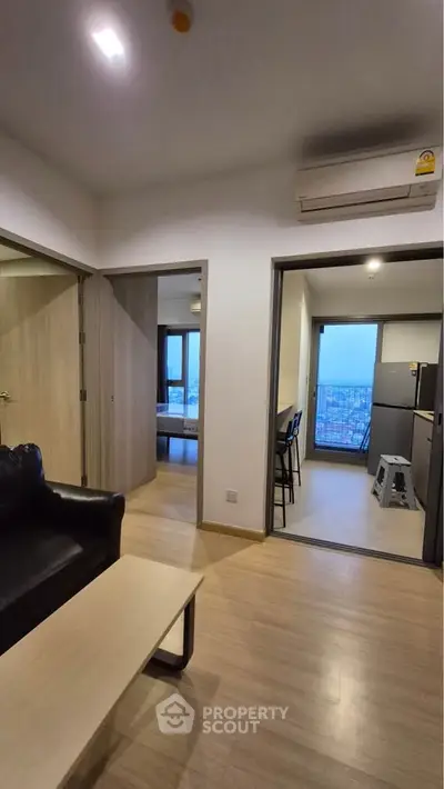 Modern apartment interior with open layout, featuring a cozy living area and a sleek kitchen with city views.