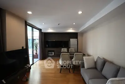 Modern living room with open layout and balcony access, featuring sleek furniture and hardwood floors.