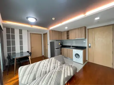 Modern open-plan living room with kitchen, featuring sleek appliances and stylish decor.