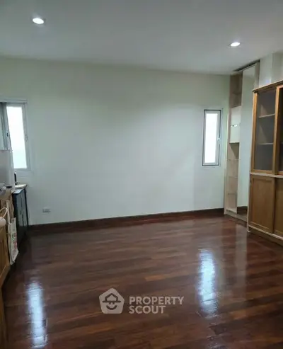 Spacious empty room with wooden flooring and natural light, ideal for customization.