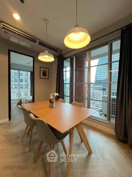 Modern dining area with wooden table, stylish chairs, and large windows offering city views.