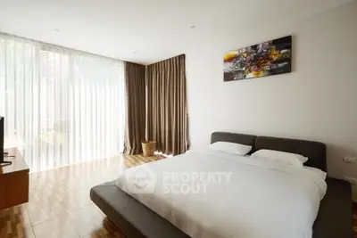 Spacious bedroom with modern decor and large windows offering natural light.