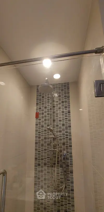 Modern bathroom shower with stylish tile design and overhead lighting.