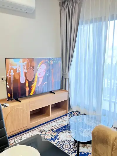 Modern living room with stylish decor, featuring a large TV and elegant curtains, perfect for relaxation.