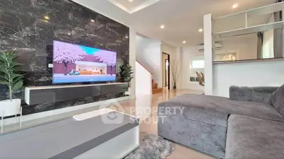 Modern living room with sleek design, featuring a large TV, plush gray sofa, and stylish decor.