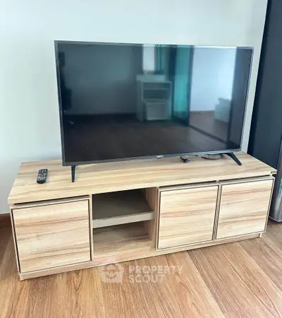 Modern living room with sleek wooden TV stand and flat-screen television.