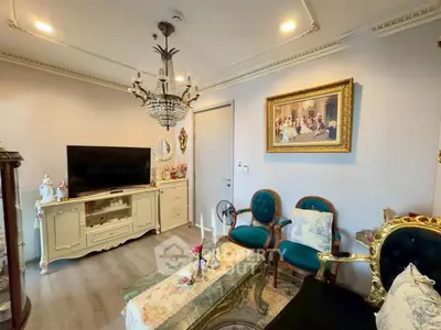 Elegant living room with vintage decor and chandelier, featuring a classic TV stand and ornate furniture.
