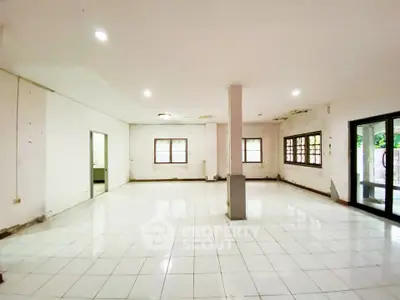 Spacious open-plan living area with tiled flooring and large windows for natural light.