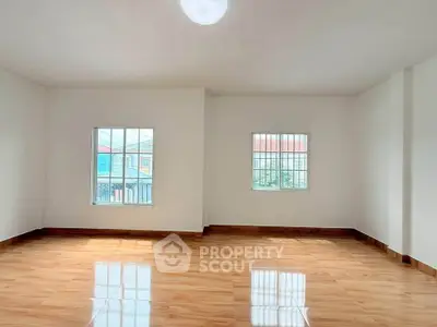 Spacious empty room with large windows and polished wooden floors, ideal for customization.