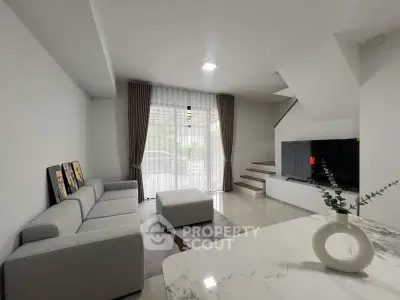 Modern living room with sleek gray sofa, marble table, and large TV, perfect for relaxation and entertainment.