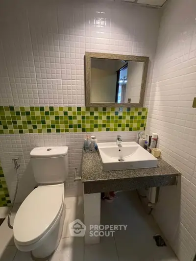 Modern bathroom with stylish green tile accents and sleek fixtures.