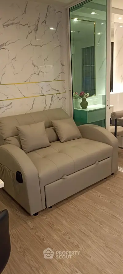 Modern living room with elegant marble walls and cozy beige sofa, perfect for relaxation.