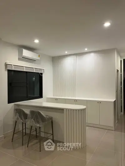 Modern kitchen with sleek white cabinetry and breakfast bar in a stylish apartment.
