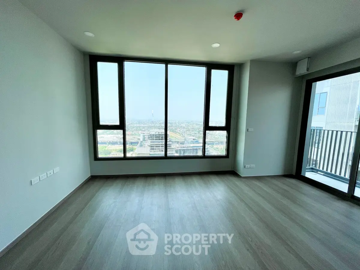 Spacious modern living room with large windows offering stunning city views and balcony access.