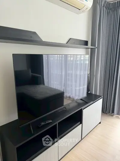Modern living room with sleek TV setup and stylish curtains, perfect for entertainment.