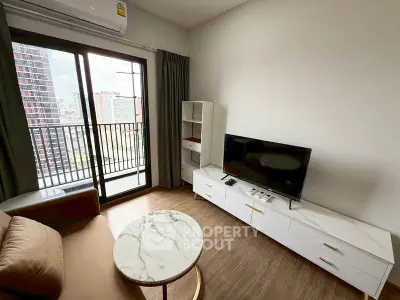 Modern living room with balcony view, featuring sleek furniture and a flat-screen TV.