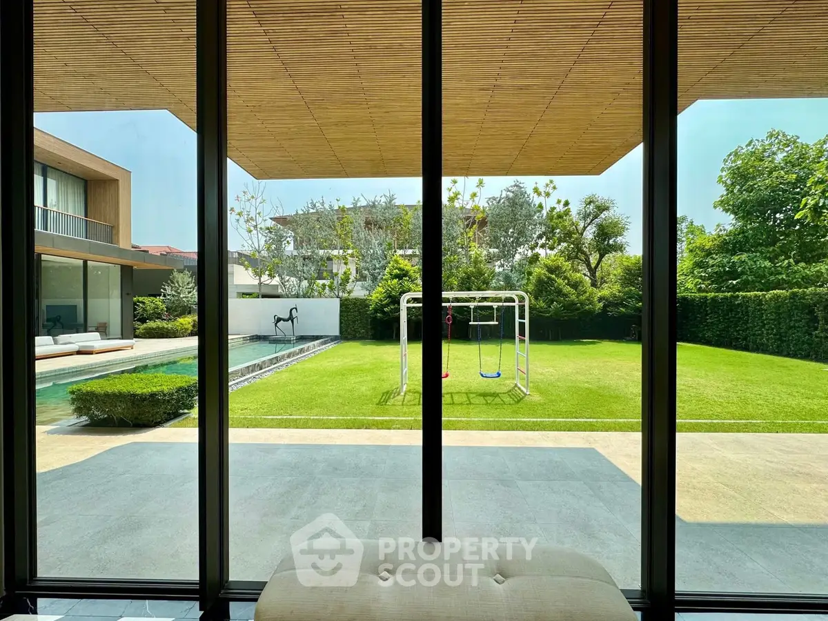 Luxurious garden view with pool and play area from modern home interior.