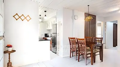 Bright dining area with wooden furniture and modern kitchen in open layout.