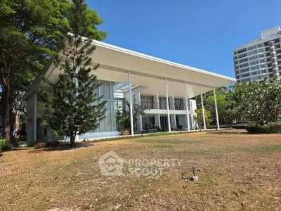 Stunning modern house with expansive glass facade and lush garden, perfect for luxury living.