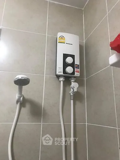Modern bathroom with sleek shower fixture and water heater on tiled wall.