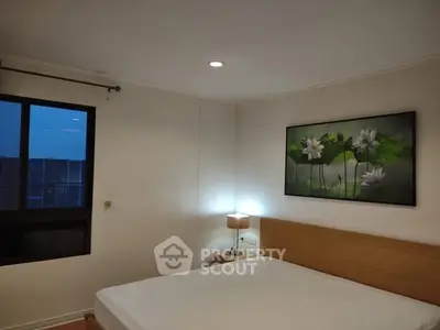 Cozy bedroom with modern decor and large window offering natural light.