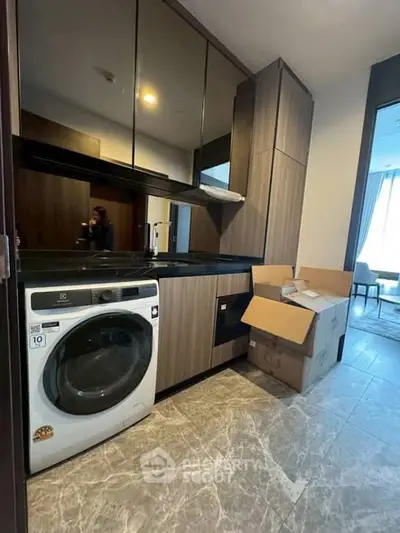 Modern kitchen with sleek cabinets and built-in washing machine in stylish apartment.