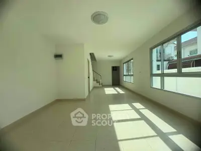Spacious sunlit living room with large windows and modern tile flooring