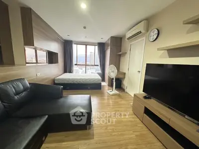 Modern studio apartment with city view, featuring sleek furniture and wooden flooring.