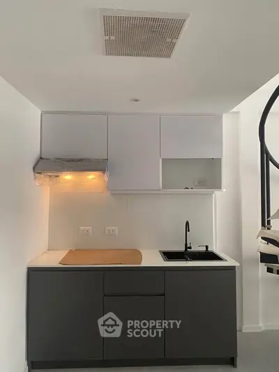 Modern minimalist kitchen with sleek cabinetry and spiral staircase
