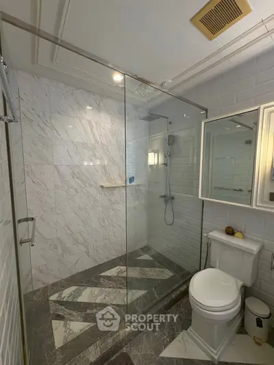 Luxurious modern bathroom with glass shower and marble tiles