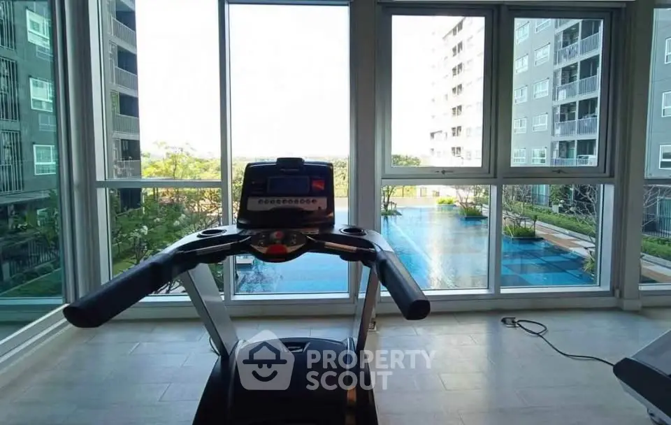 Modern gym with treadmill overlooking a stunning pool view in a high-rise building.