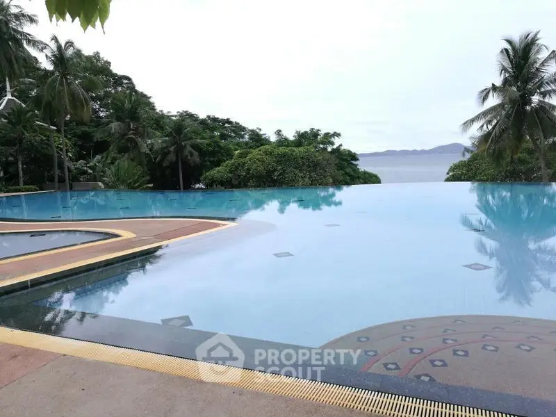 Stunning infinity pool with ocean view surrounded by lush greenery and palm trees.