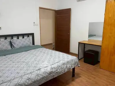 Cozy bedroom with modern decor and wooden flooring, featuring a comfortable bed and a stylish desk.